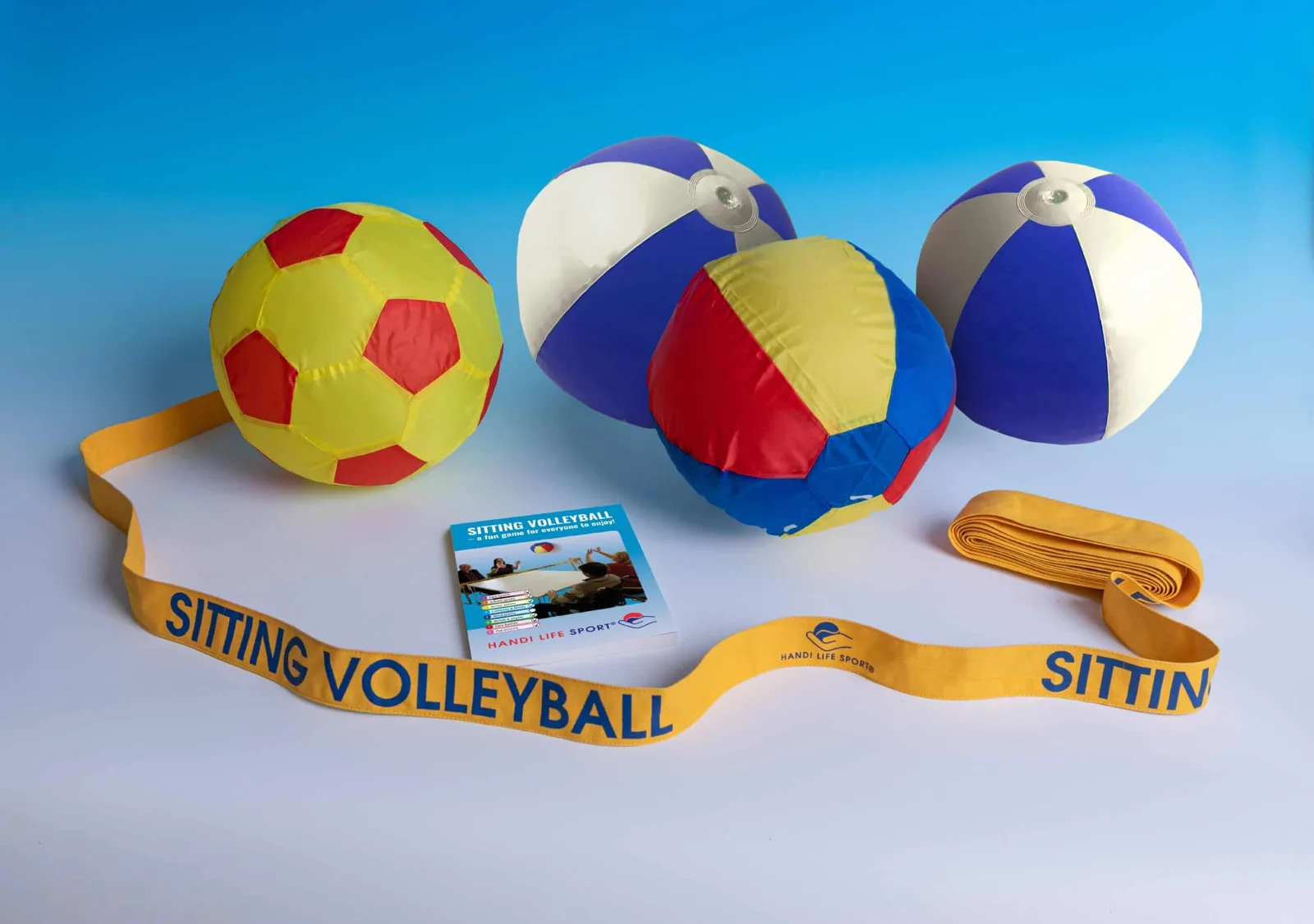 A volleyball set: a yellow-and-red ball, blue-and-white beach balls and a yellow “Sitting Volleyball” net band.