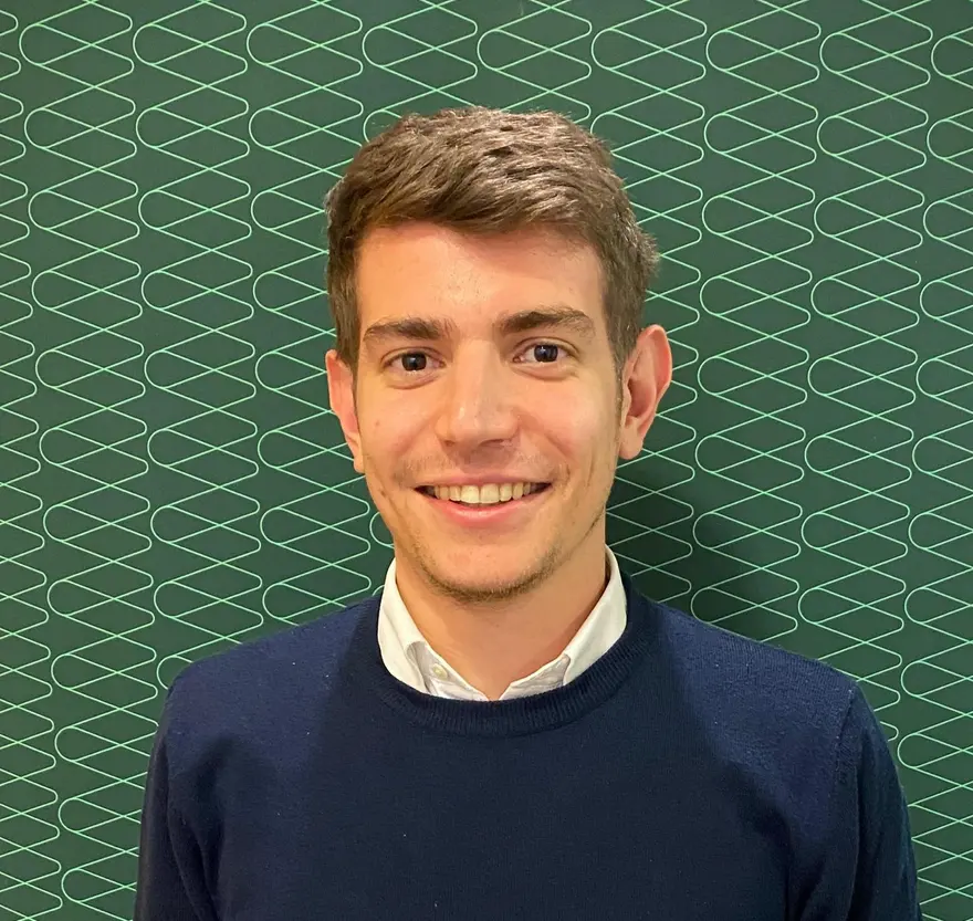 Daniele Quinto smiling in a navy jumper and white shirt